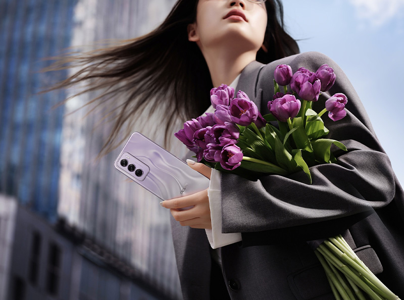 A person holding flowers and a phone
    
    Description automatically generated